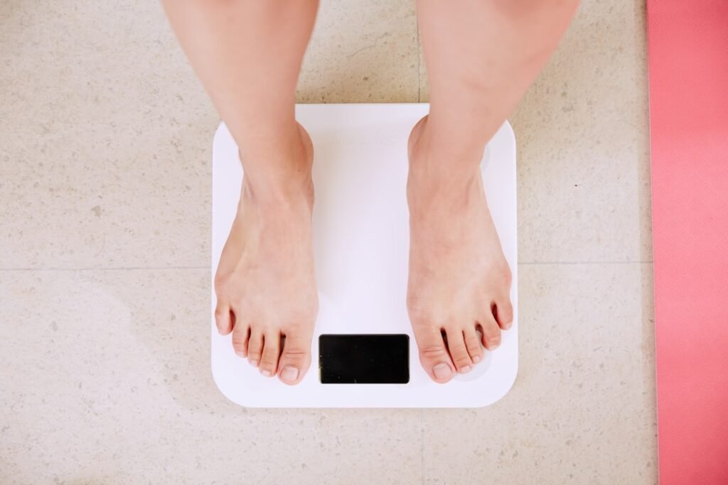 Person on scale reviewing ideal weight formulas and body frame size