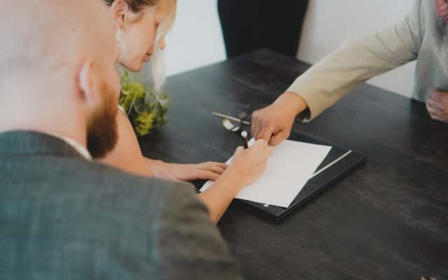 Couple signing mortgage documents at a desk