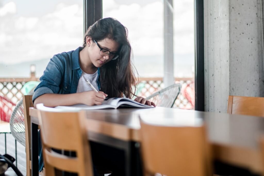 Student studying with textbooks calculating what grade is needed on the final exam