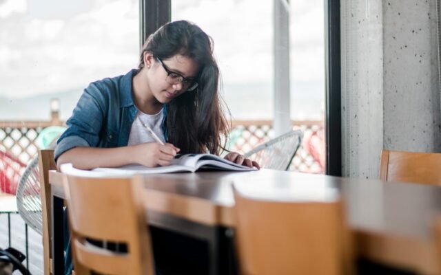Student studying with textbooks calculating what grade is needed on the final exam