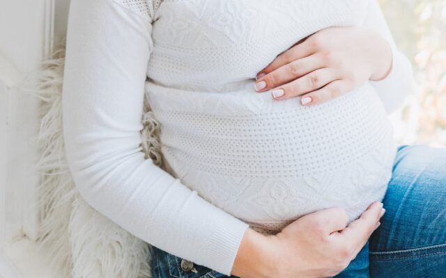 Pregnant woman holding her belly representing pregnancy milestones by trimester