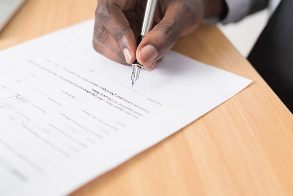 Person writing on paperwork representing questions to ask before signing a loan agreement