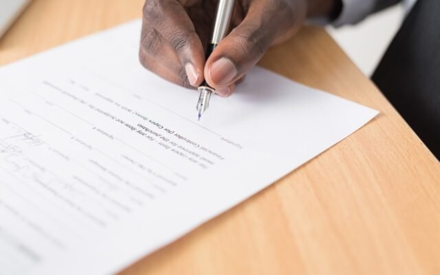 Person writing on paperwork representing questions to ask before signing a loan agreement